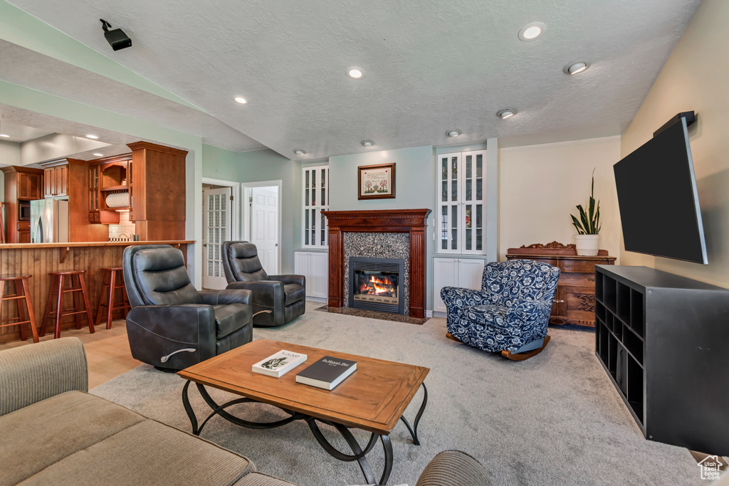 Living area featuring recessed lighting, a tiled fireplace, light carpet, and a textured ceiling