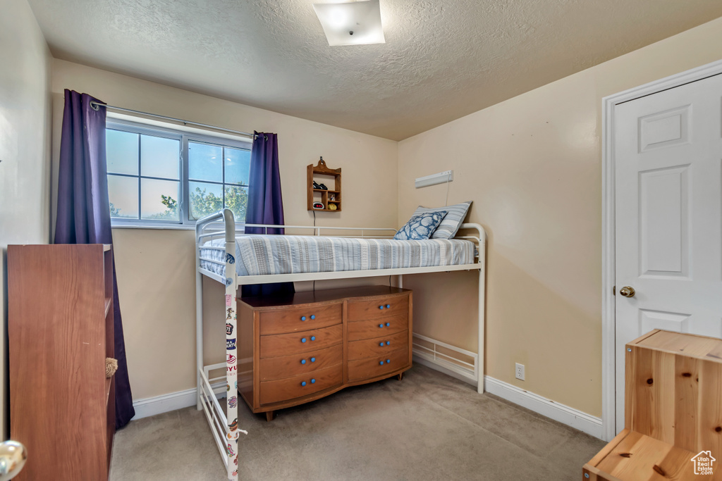 Bedroom featuring carpet flooring, a textured ceiling, and baseboards