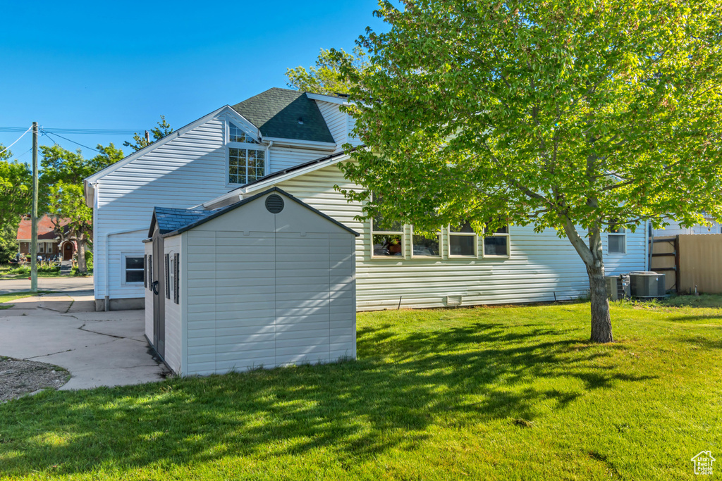 Rear view of house featuring central air condition unit and a lawn