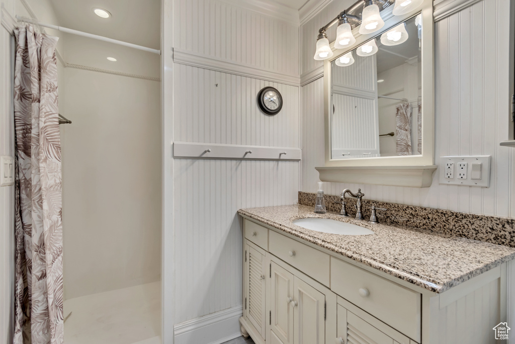 Bathroom with curtained shower, vanity, and ornamental molding