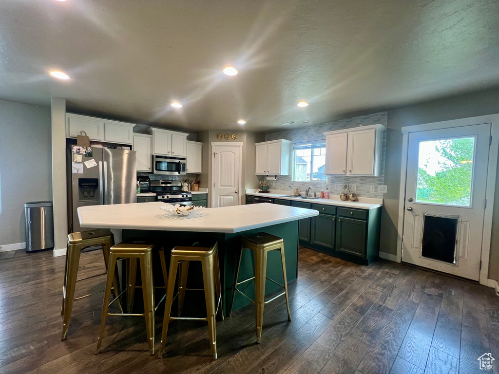 Kitchen with a center island, baseboards, appliances with stainless steel finishes, tasteful backsplash, and dark wood-style floors