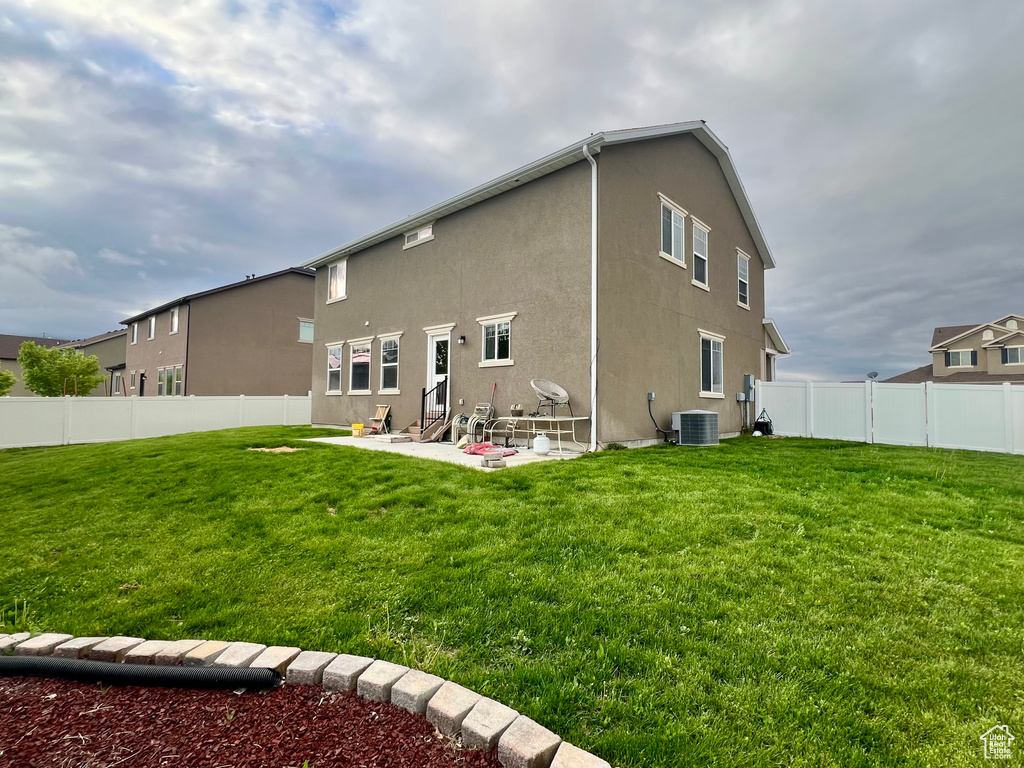 Rear view of property featuring a yard, stucco siding, a fenced backyard, and a patio