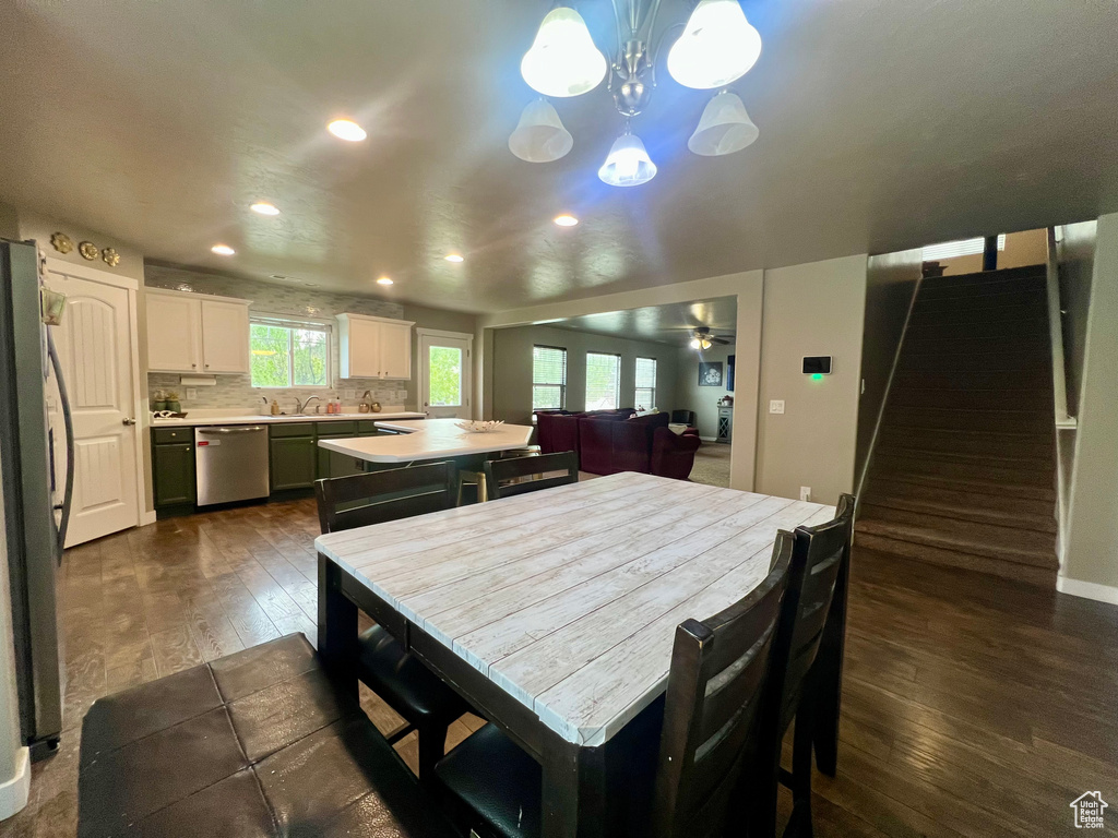 Dining area with recessed lighting, baseboards, ceiling fan with notable chandelier, dark wood-type flooring, and stairway