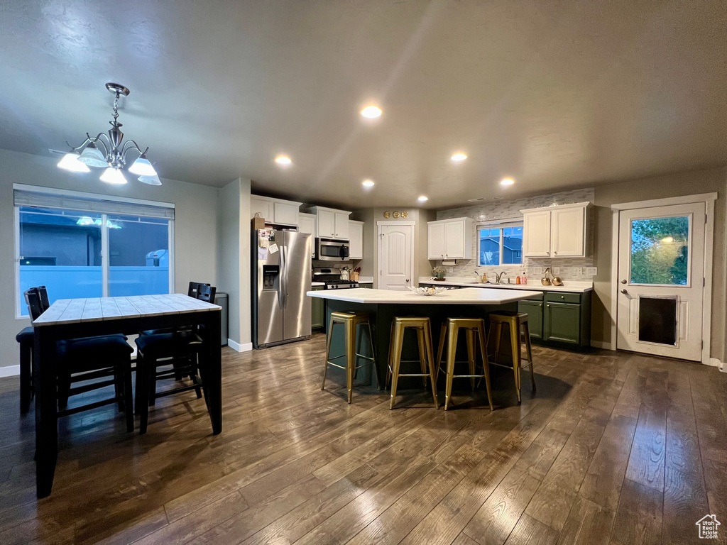 Kitchen featuring stainless steel appliances, dark wood finished floors, light countertops, a notable chandelier, and a kitchen island