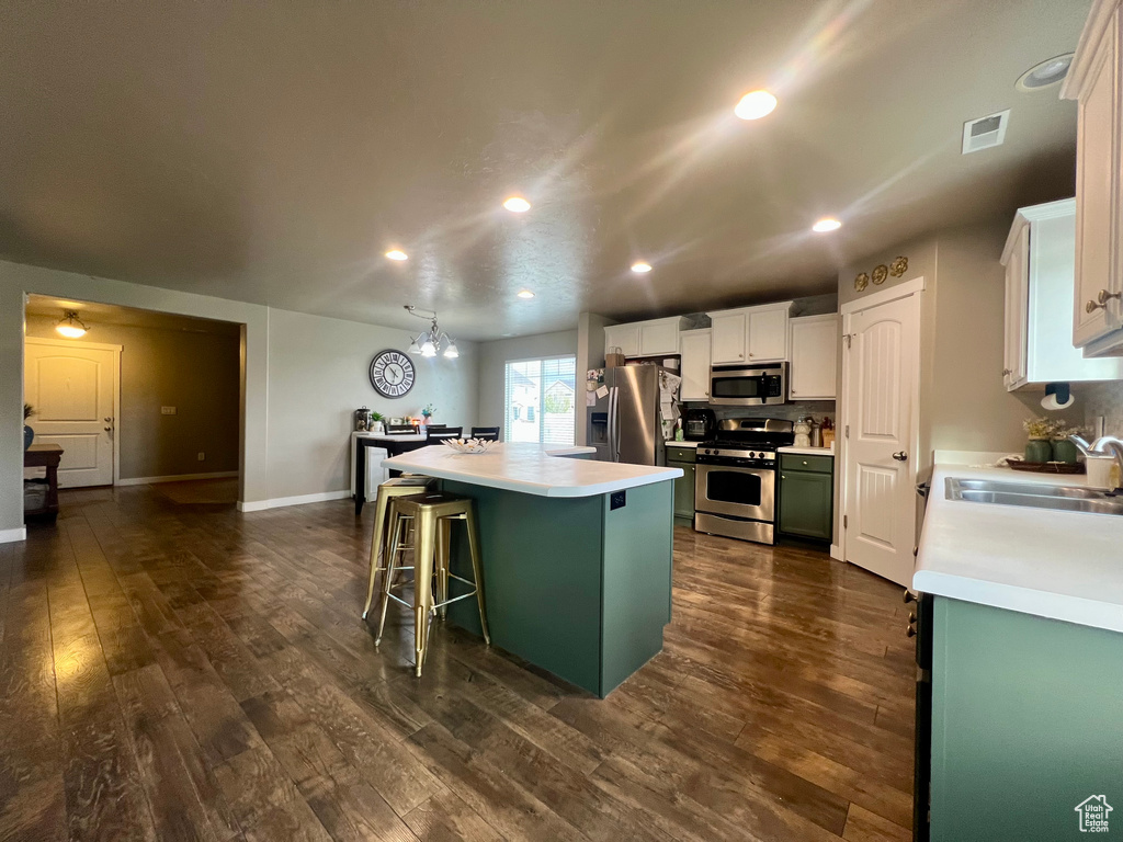 Kitchen featuring a sink, a breakfast bar, light countertops, a kitchen island, and appliances with stainless steel finishes
