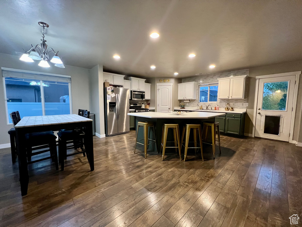 Kitchen with a notable chandelier, stainless steel appliances, a center island, a kitchen breakfast bar, and light countertops