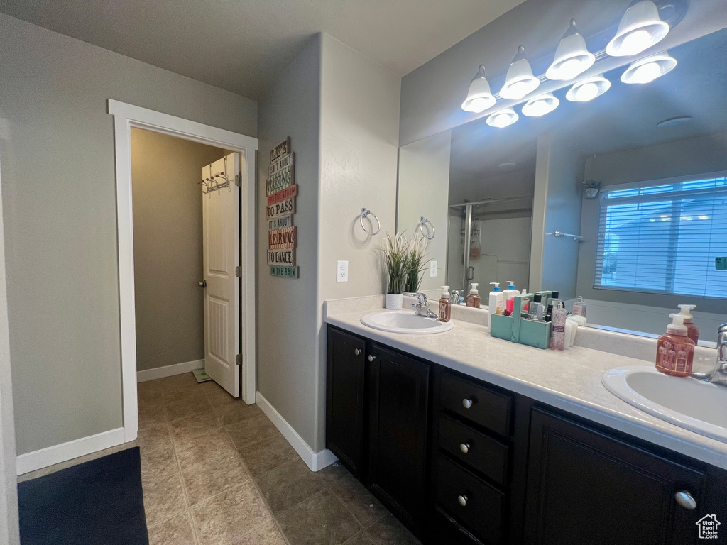 Bathroom featuring double vanity, an enclosed shower, baseboards, and a sink
