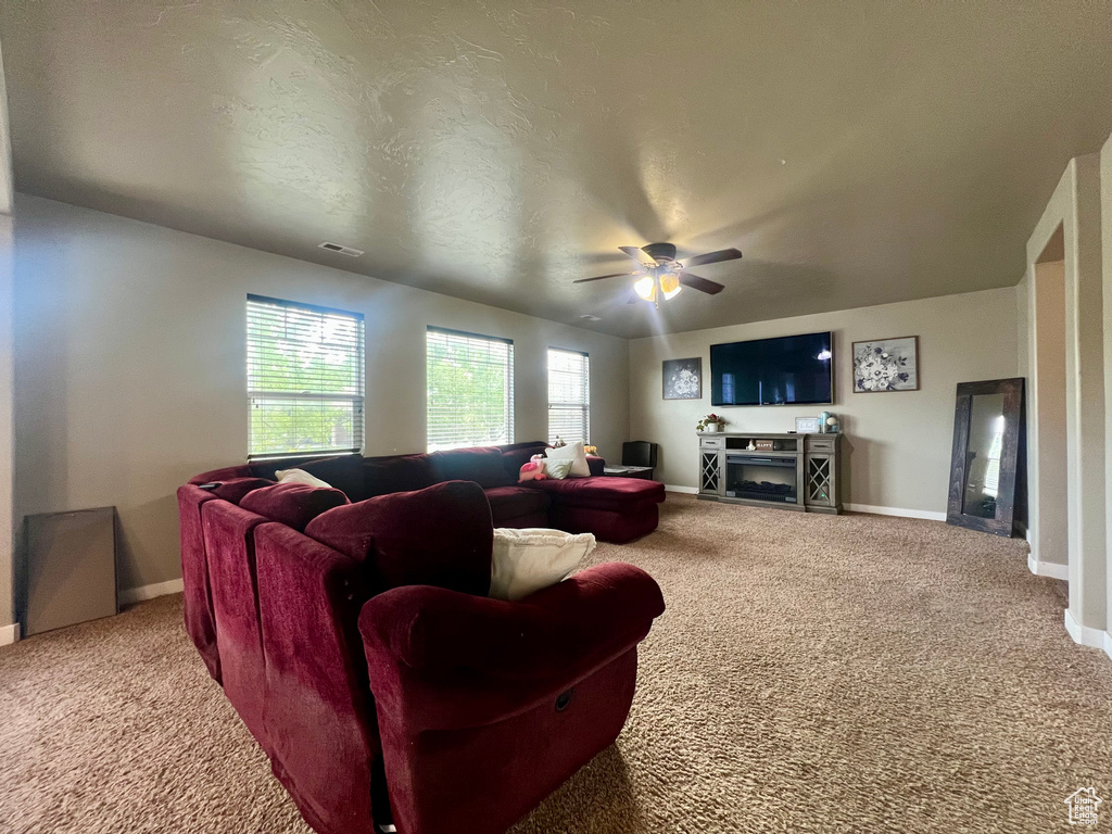 Living room featuring baseboards, carpet flooring, visible vents, and ceiling fan