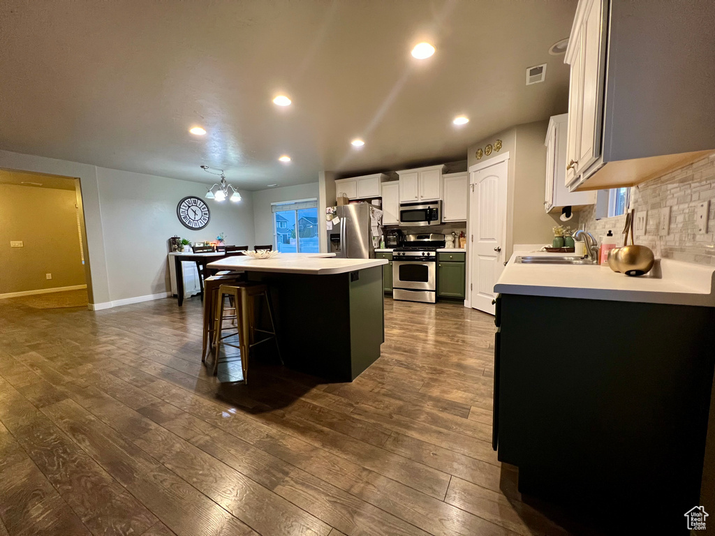 Kitchen featuring a sink, stainless steel appliances, visible vents, backsplash, and a kitchen island