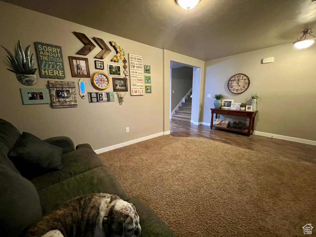Carpeted living room with stairway and baseboards