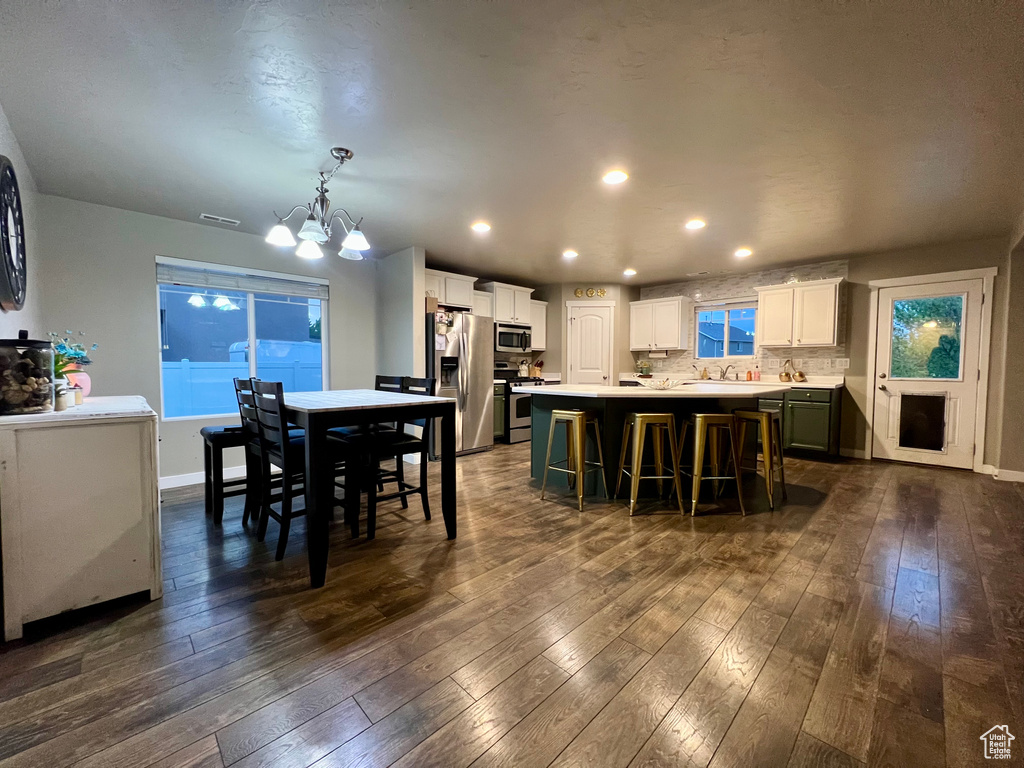 Dining space featuring an inviting chandelier, baseboards, dark wood-type flooring, and visible vents