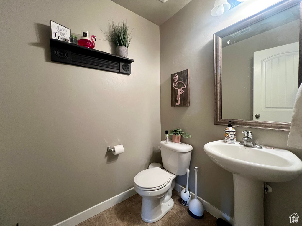 Bathroom with baseboards, toilet, visible vents, a sink, and tile patterned flooring