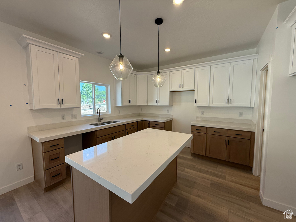 Kitchen with wood finished floors, white cabinets, recessed lighting, a center island, and decorative light fixtures