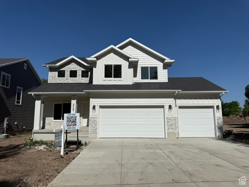 View of front of house featuring stone siding, driveway, board and batten siding, and a garage