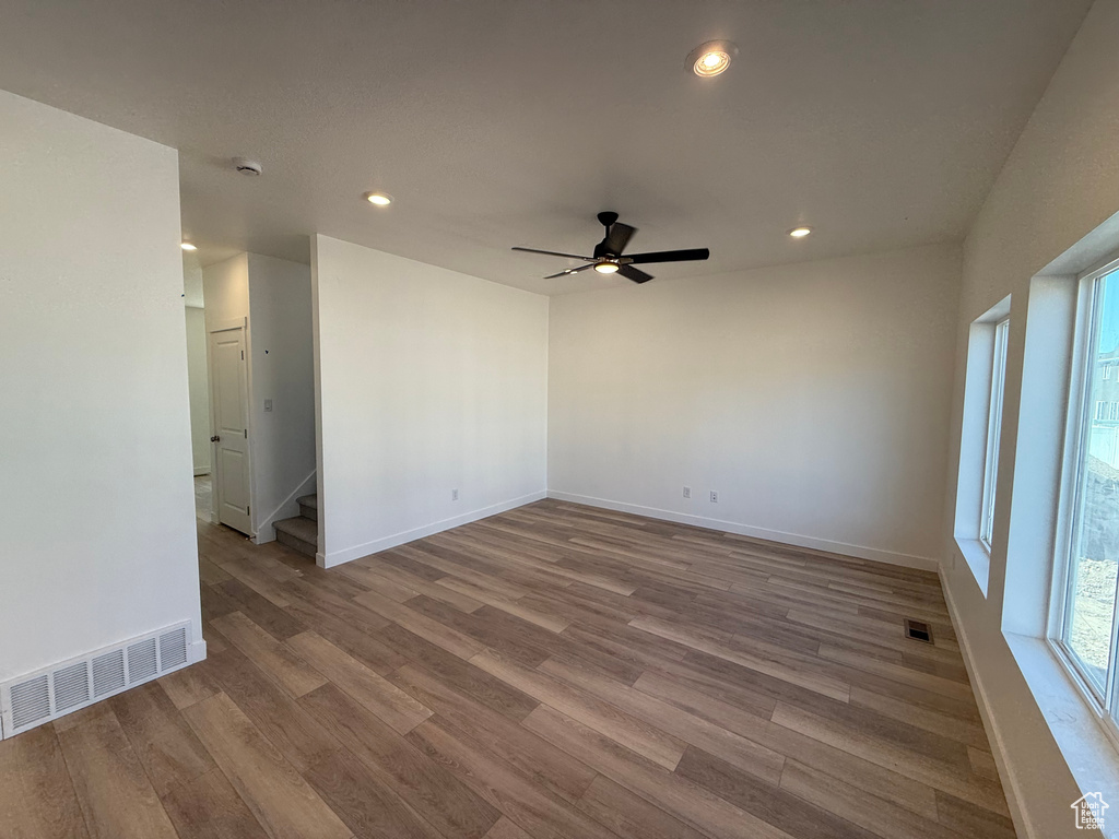 Empty room with wood finished floors, recessed lighting, ceiling fan, stairs, and a smoke detector