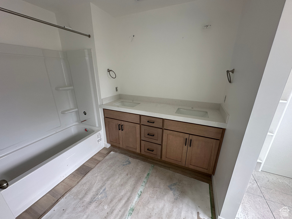 Full bath featuring a sink,  shower combination, double vanity, and baseboards