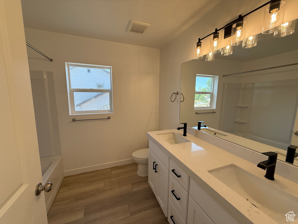 Bathroom featuring double vanity, wood finished floors, and bathing tub / shower combination
