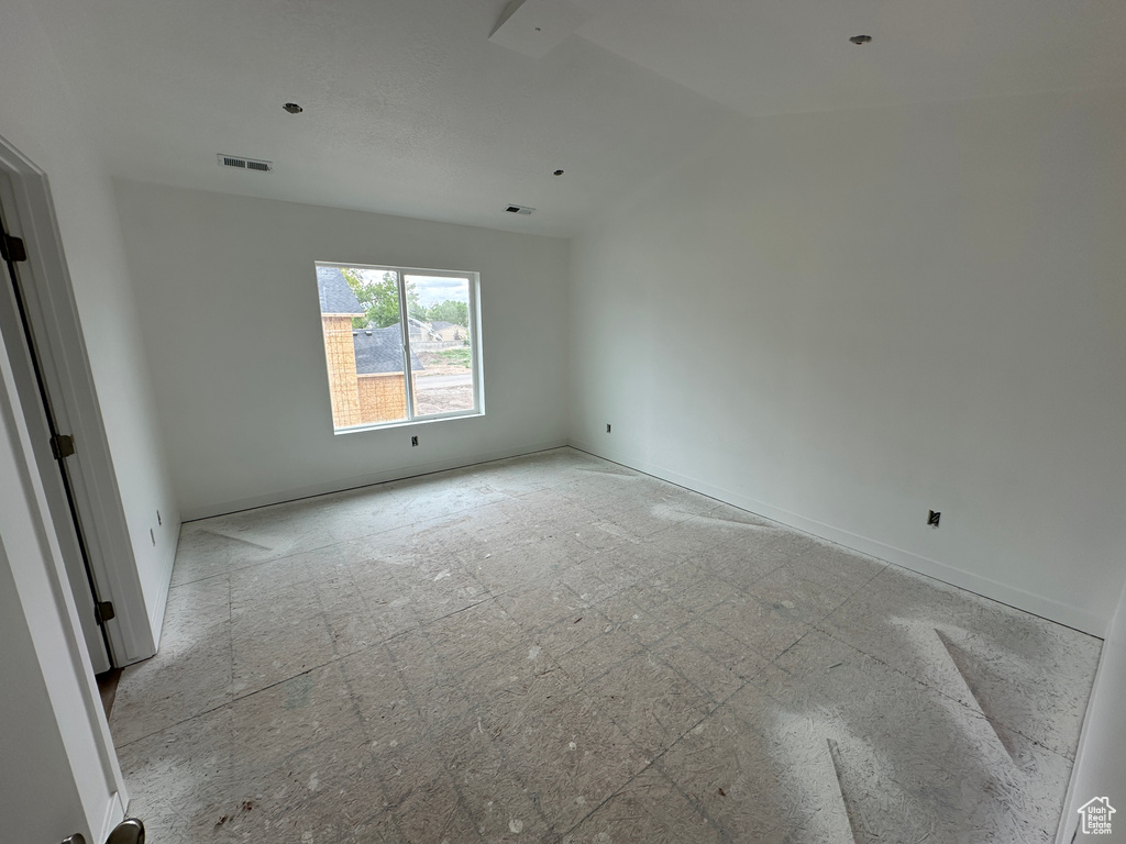 Spare room featuring visible vents, baseboards, and lofted ceiling