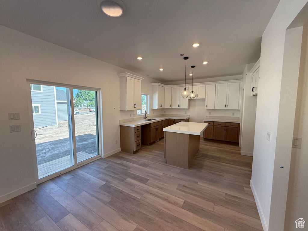 Kitchen with recessed lighting, light wood-style floors, a center island, white cabinets, and light countertops