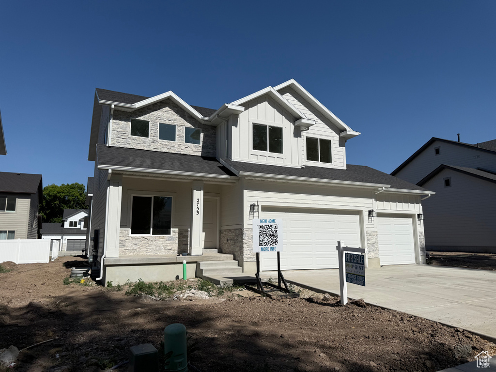 View of front of property with covered porch, board and batten siding, driveway, and stone siding
