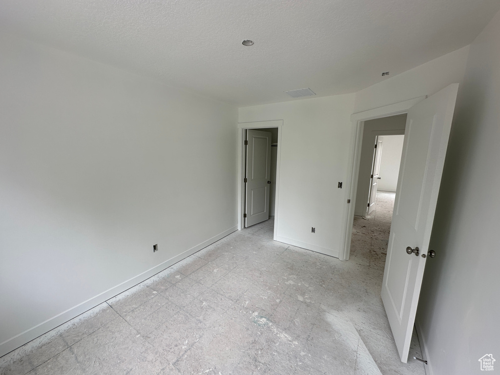 Unfurnished bedroom with baseboards, visible vents, and a textured ceiling