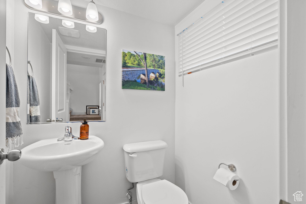 Half bathroom with toilet, baseboards, and visible vents