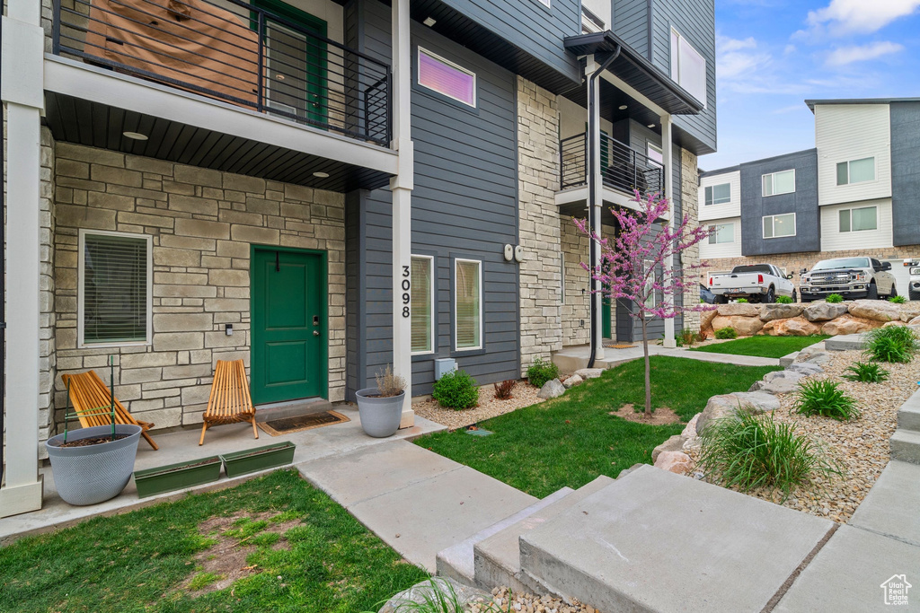 Entrance to property with stone siding and a balcony