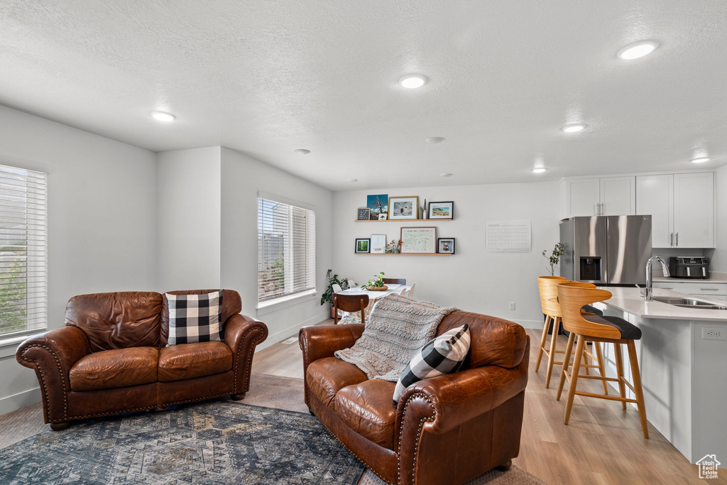 Living area with recessed lighting, baseboards, and light wood-style floors