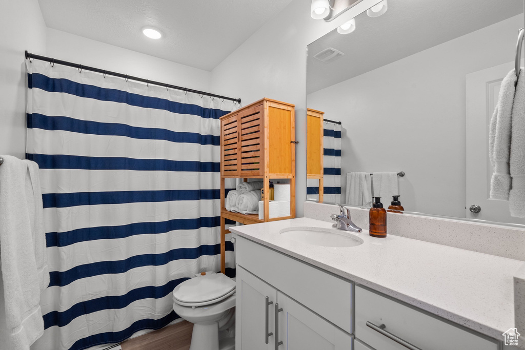 Bathroom with toilet, visible vents, a shower with shower curtain, vanity, and wood finished floors