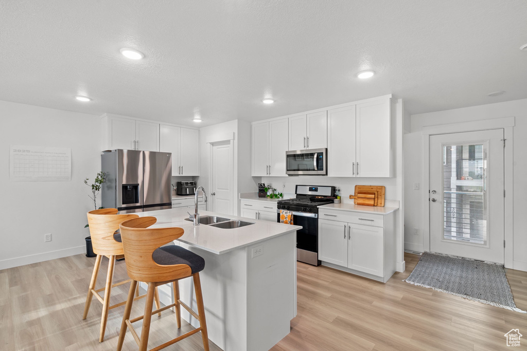 Kitchen with recessed lighting, a sink, a kitchen bar, stainless steel appliances, and a kitchen island with sink