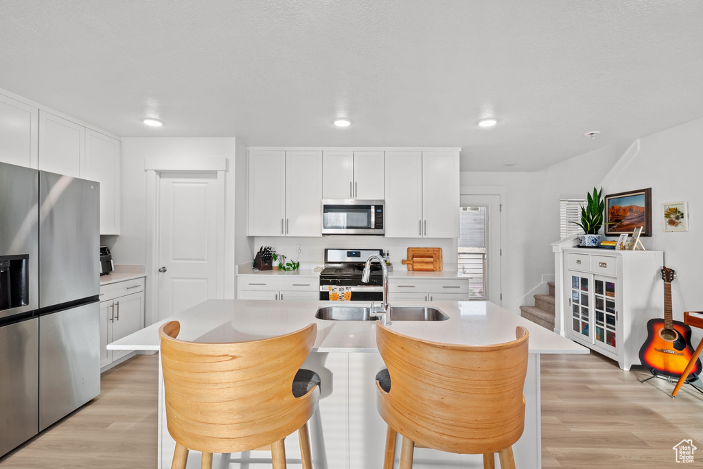 Kitchen featuring a sink, stainless steel appliances, light countertops, and light wood-style floors