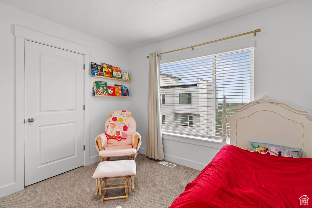 Carpeted bedroom with multiple windows, visible vents, and baseboards
