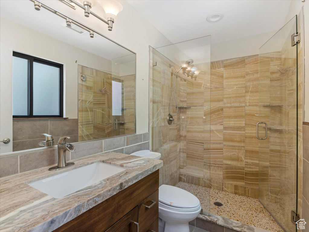 Full bath featuring a shower stall, tile walls, vanity, and toilet