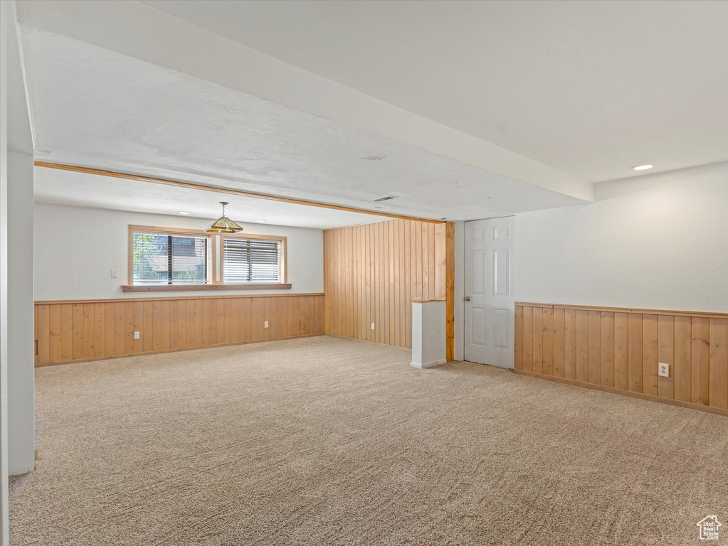 Carpeted spare room featuring wood walls and a wainscoted wall