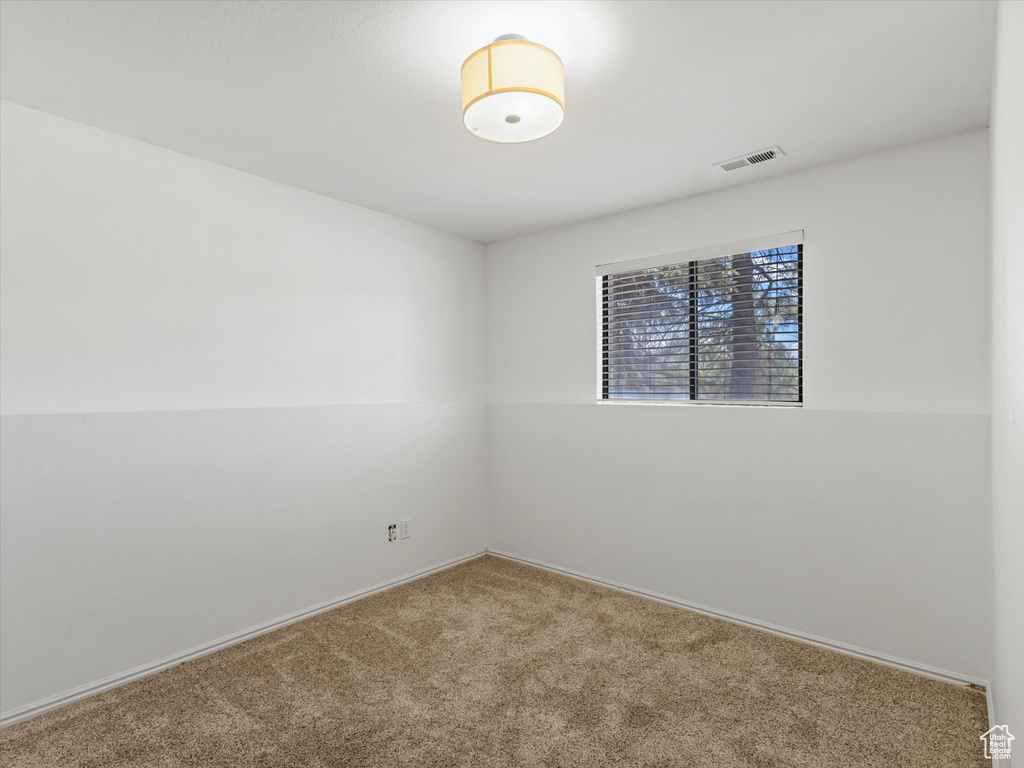 Carpeted empty room with baseboards and visible vents