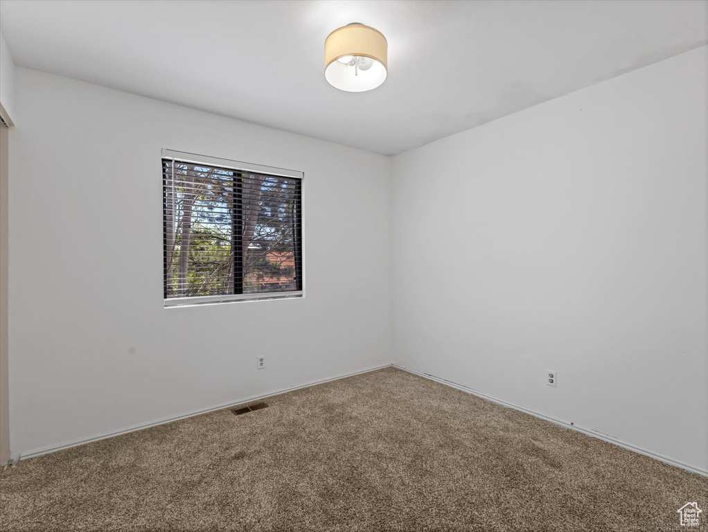 Carpeted empty room with visible vents and baseboards