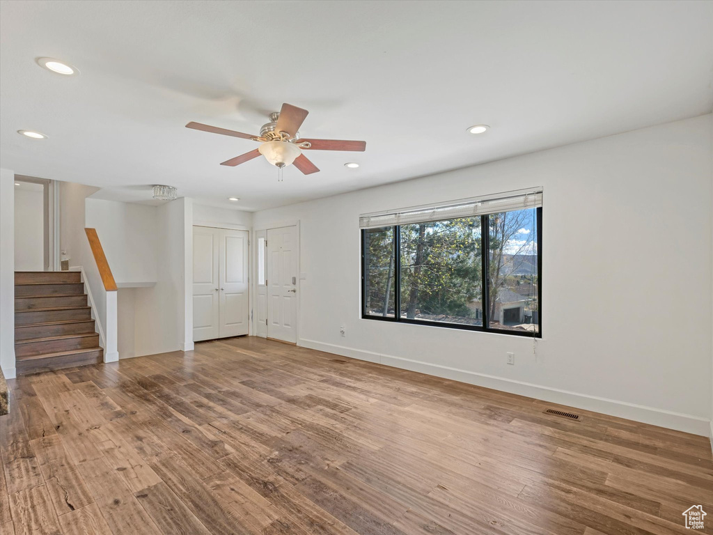 Empty room featuring stairs, wood finished floors, baseboards, and recessed lighting