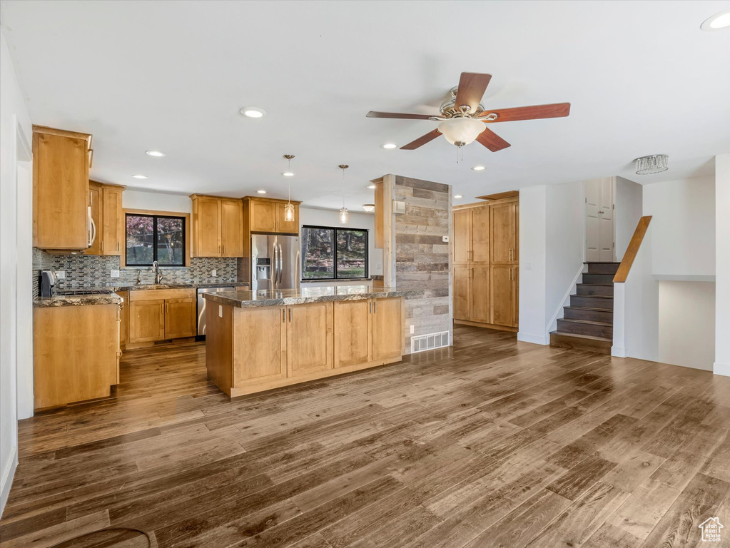 Kitchen with backsplash, dark wood-type flooring, a ceiling fan, and appliances with stainless steel finishes