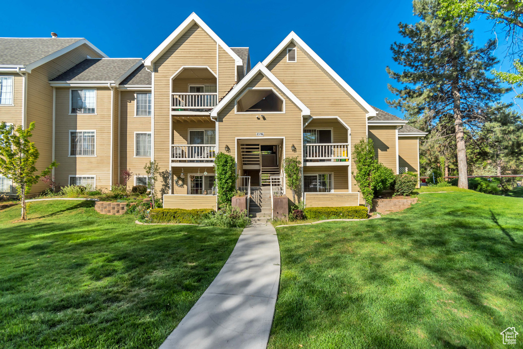 View of front of house featuring a front lawn and a balcony