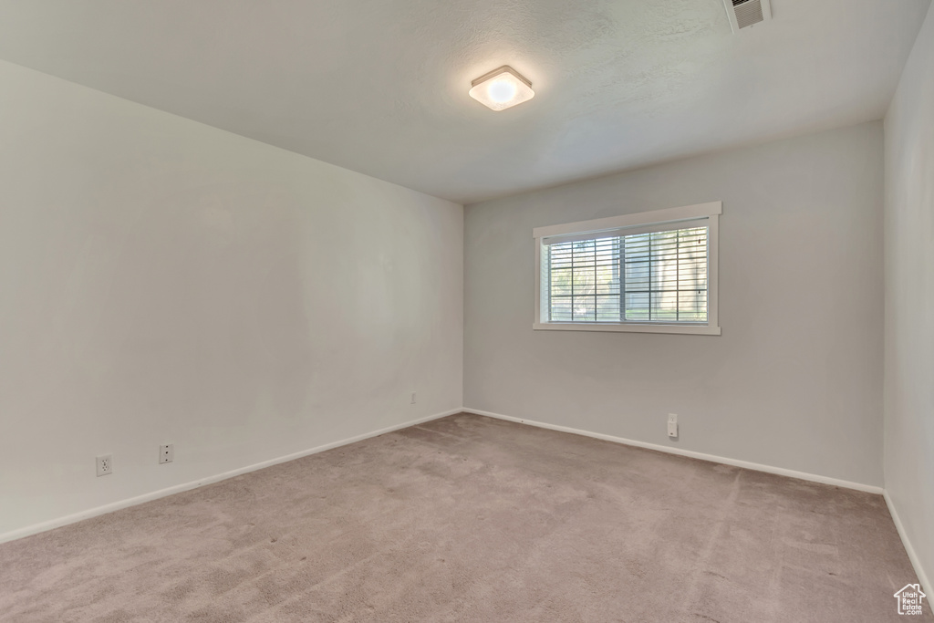 Carpeted empty room with baseboards and visible vents