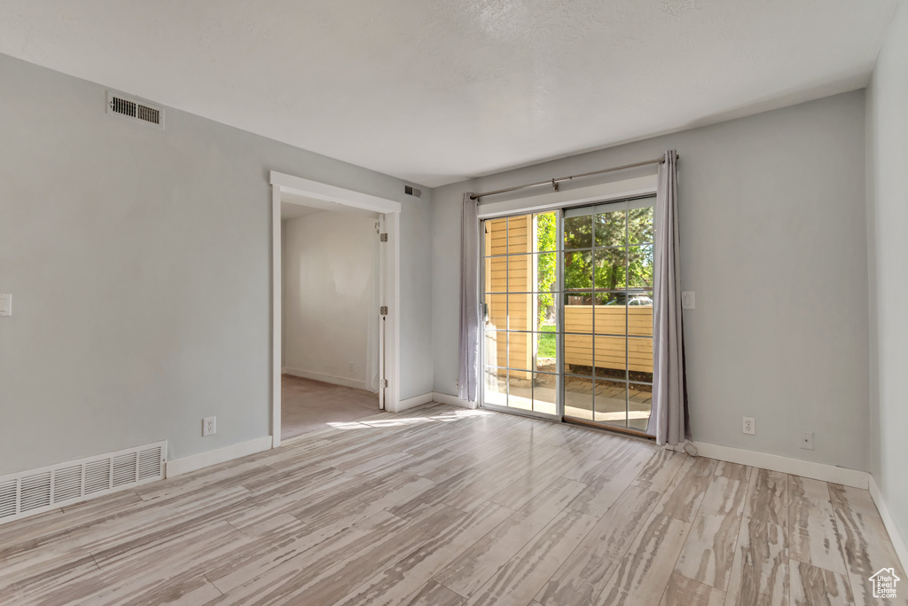 Spare room featuring baseboards, visible vents, and wood finished floors