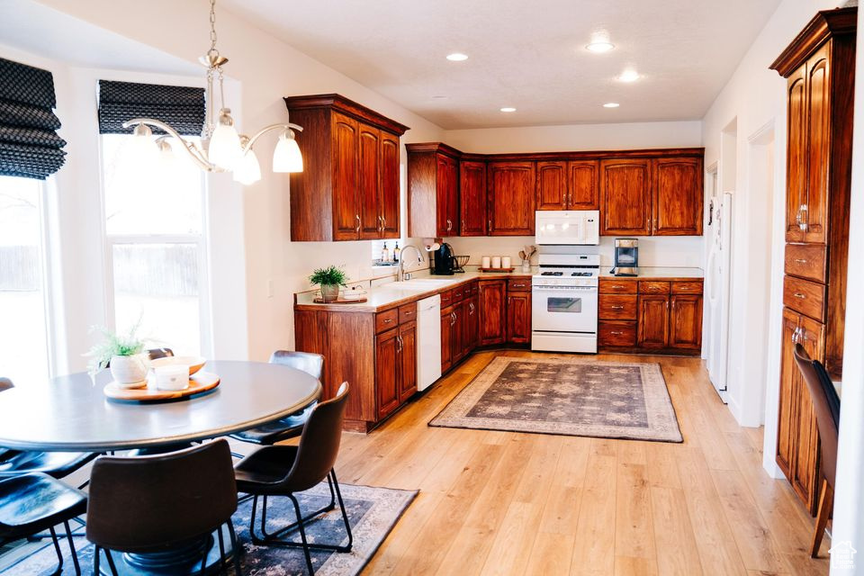 Kitchen with white appliances, light countertops, a sink, and light wood-style floors