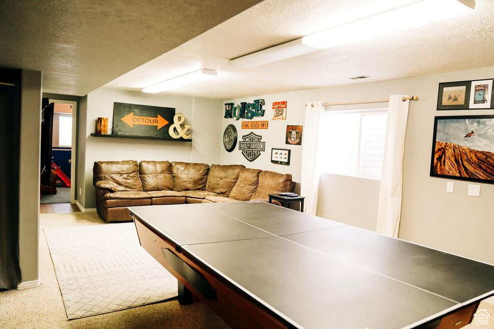Recreation room with carpet floors, visible vents, and a textured ceiling