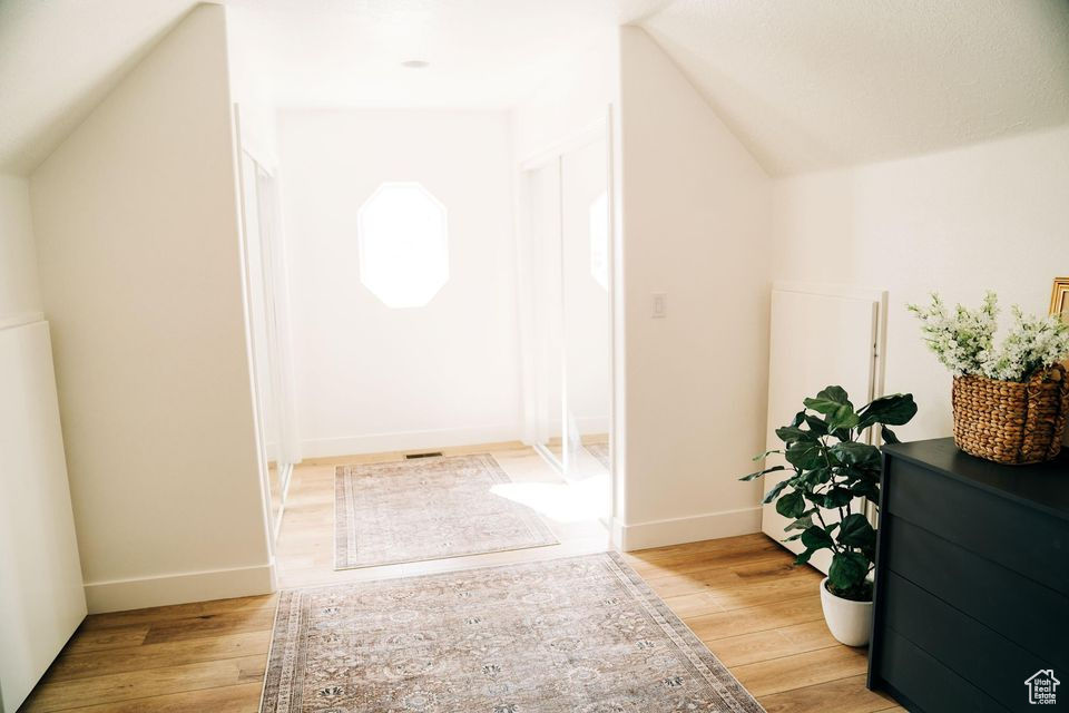Additional living space with vaulted ceiling, baseboards, and light wood-type flooring