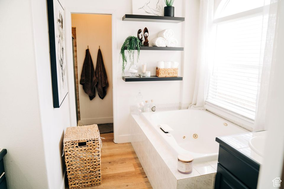 Bathroom with vanity, wood finished floors, and a whirlpool tub