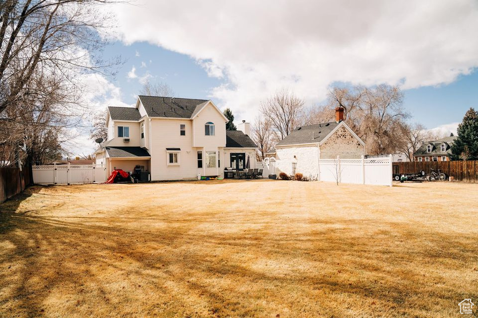 Rear view of property with a fenced backyard, a deck, and a yard