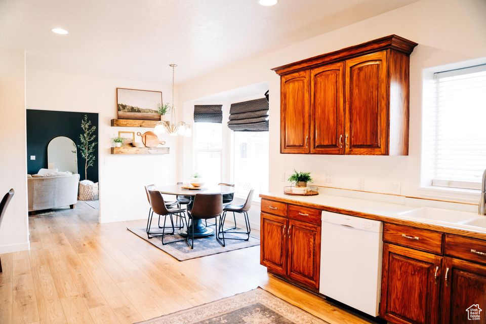 Kitchen featuring white dishwasher, light countertops, light wood-style flooring, and a sink