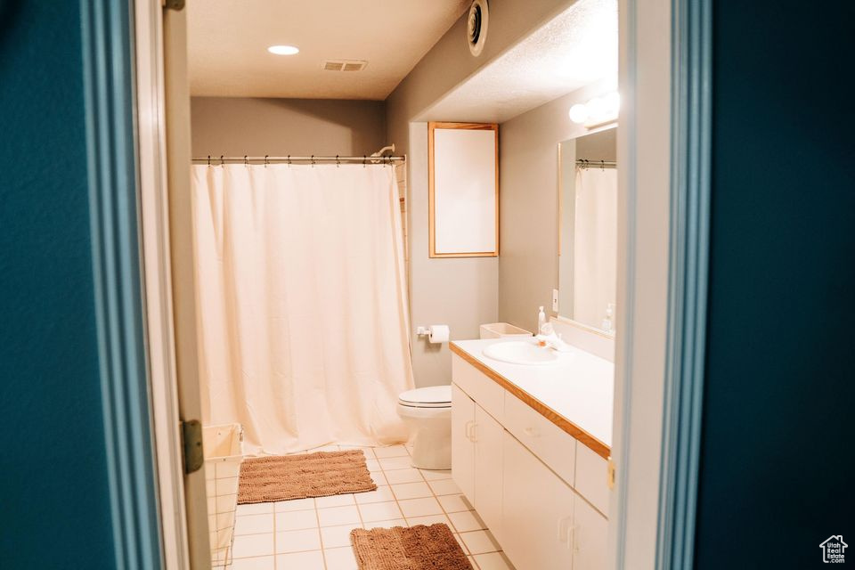 Bathroom with toilet, visible vents, a shower with shower curtain, tile patterned floors, and vanity