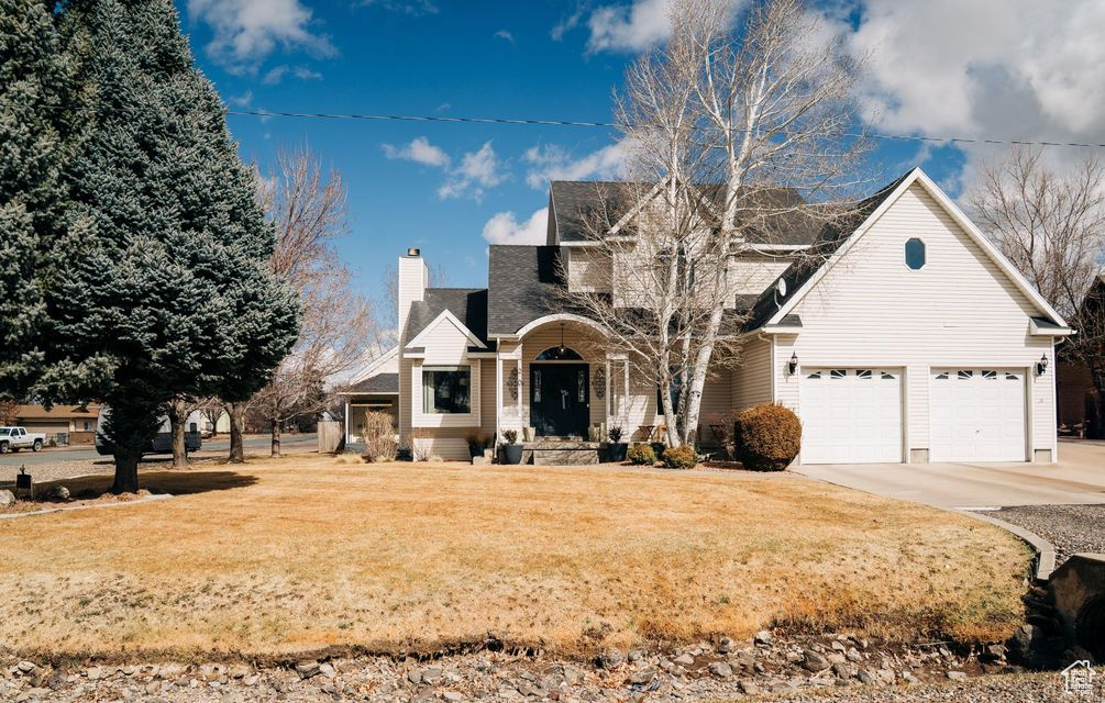 View of front of property with a porch, concrete driveway, a chimney, and a front yard
