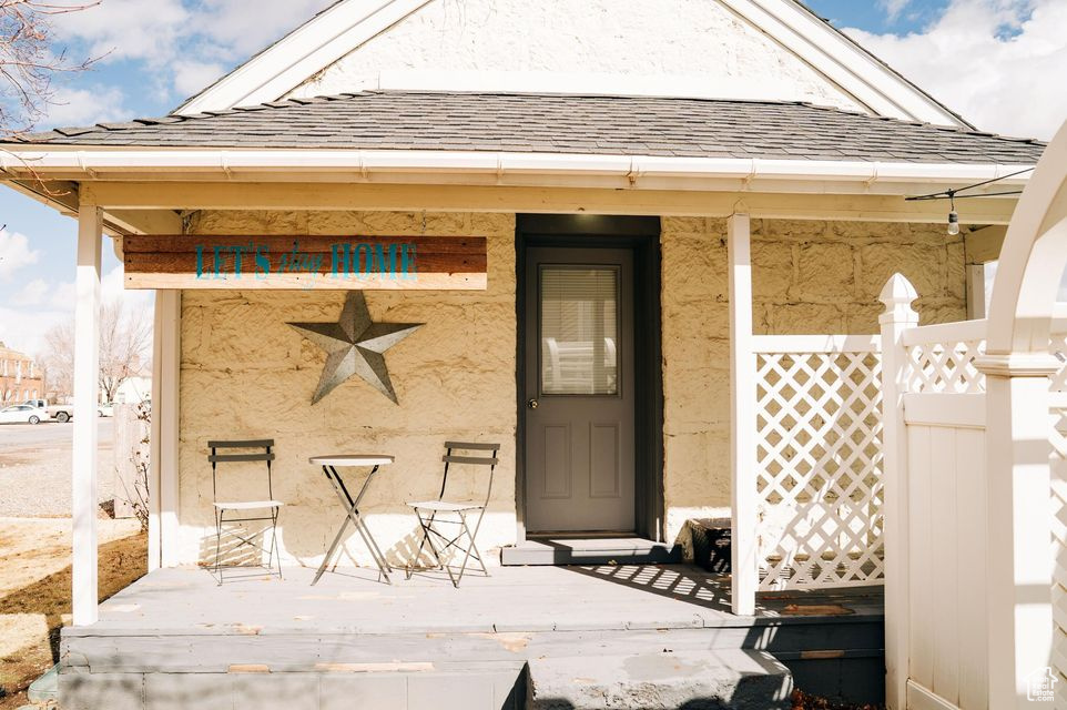 View of exterior entry featuring stucco siding and roof with shingles
